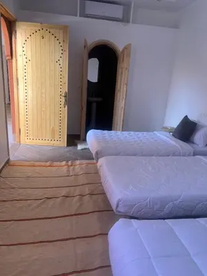 a room with three beds and a door to a room at Rose Garden Dades in Kalaat MGouna