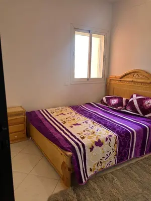 a bedroom with a bed with purple sheets and a window at iliy House in Mrhila