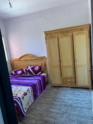 a bedroom with a bed and two wooden cabinets at iliy House in Mrhila