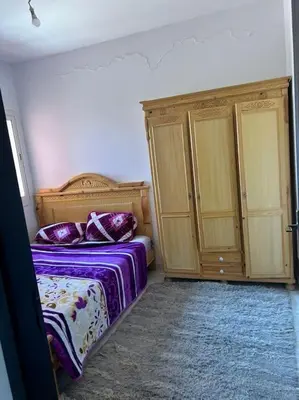 a bedroom with a bed and two wooden cabinets at iliy House in Mrhila