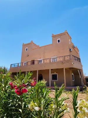 a large brown building with bushes in front of it at Kasbah Talala in Skoura