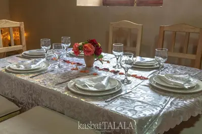 a table with plates and glasses and a vase of flowers at Kasbah Talala in Skoura