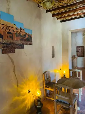 a room with a table and chairs and a wall with a painting at Kasbah Talala in Skoura