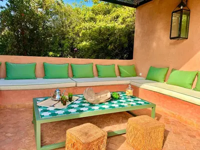 a couch with green pillows and a table on a patio at Palais Danka in Sraïri