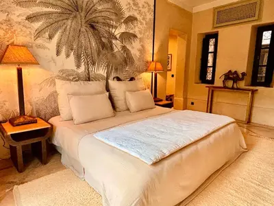a bedroom with a white bed with a palm tree on the wall at Palais Danka in Sraïri