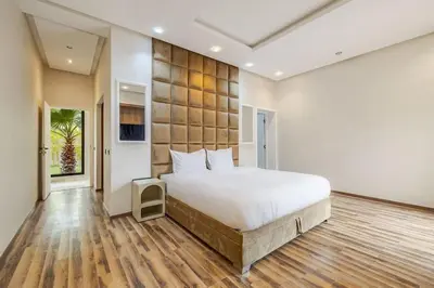 a bedroom with a large white bed and wooden floors at Villa de plain-pied avec piscine chauffée à Marrakech in Marrakech