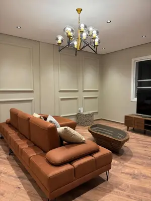 a living room with a brown couch and a chandelier at Suite Bahiya 19 in Fès