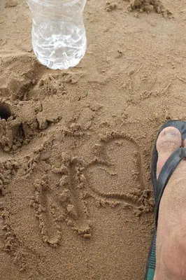 a person writing in the sand next to a water bottle at imintanoute in Kasba Aït Youdi