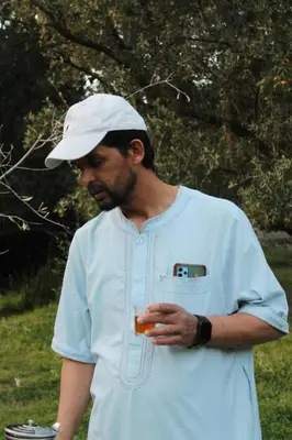 a man wearing a white hat holding a drink at imintanoute in Kasba Aït Youdi
