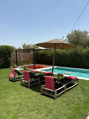 a group of chairs and an umbrella next to a pool at Villa soléa - Route Ouarzazate in Marrakech