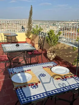 a patio with two tables and chairs on a balcony at Dar Fez Arinas - Rooftop View - Central Fez in Fès