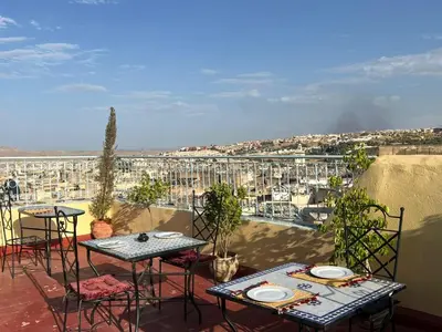 a balcony with tables and chairs and a view of a city at Dar Fez Arinas - Rooftop View - Central Fez in Fès