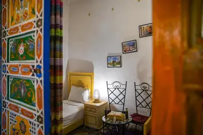 a small bedroom with a bed and a table at Dar Fez Arinas - Rooftop View - Central Fez in Fès