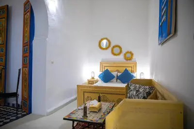 a bedroom with a bed with blue pillows and a table at Dar Fez Arinas - Rooftop View - Central Fez in Fès