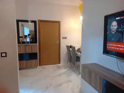 a living room with a television and a dining room at appartement meublé moderne in Fès