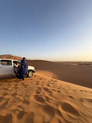 a man standing next to a car in the desert at Desert Bliss in Merzouga