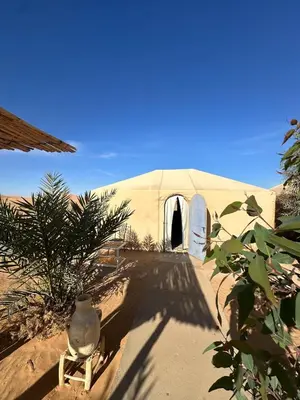 a tent in the desert with a vase in front of it at Desert Bliss in Merzouga