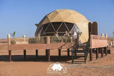 a group of people standing in front of a yurt at Sahara Dome Camp in Merzouga