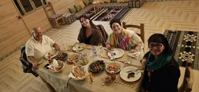 a group of people sitting at a table with food at Sahara Dome Camp in Merzouga