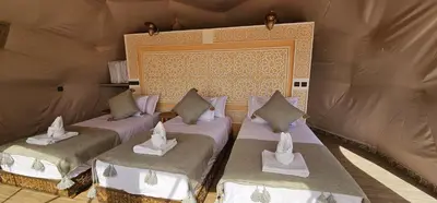 a room with three beds in a tent at Sahara Dome Camp in Merzouga