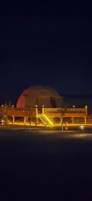 a domed building with a dome in the background at night at Sahara Dome Camp in Merzouga