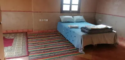a bedroom with a blue bed and a rug at DAR AGLMOUZ -Ighir aghzzaf- in Kalaat MGouna