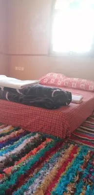 a bed with a multicolored rug on the floor at DAR AGLMOUZ -Ighir aghzzaf- in Kalaat MGouna