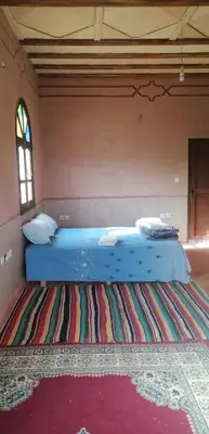 a large bed in a room with a rug at DAR AGLMOUZ -Ighir aghzzaf- in Kalaat MGouna