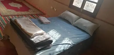a bed with blankets and pillows on it in a room at DAR AGLMOUZ -Ighir aghzzaf- in Kalaat MGouna