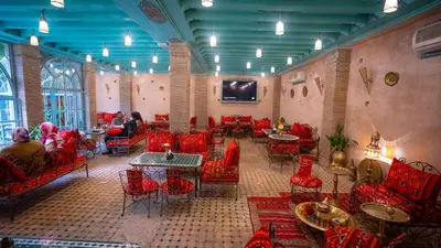 a restaurant with red chairs and tables in a room at Riad Golden Mansour in Meknès