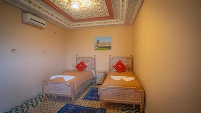 two beds in a room with a ceiling at Riad Golden Mansour in Meknès
