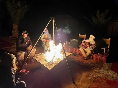 a group of people sitting around a fire at Luxury Merzouga Camp in Merzouga