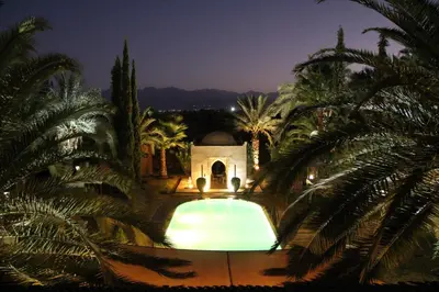 a swimming pool in front of a building with palm trees at Palais Celoa in Marrakech