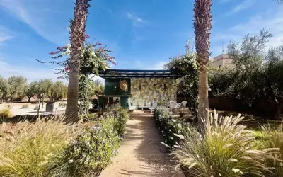 a garden with two palm trees and a building at Villa Sbaa Marrakech in Marrakech