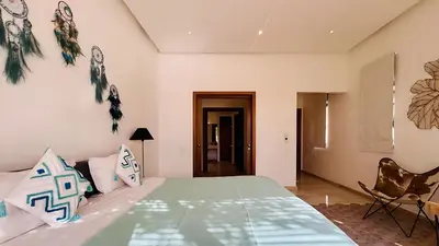 a bedroom with a green bed and a chair at Villa Sbaa Marrakech in Marrakech