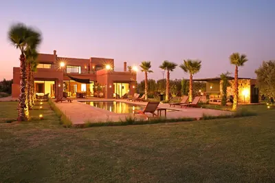 a house with a swimming pool and palm trees at Villa Sbaa Marrakech in Marrakech