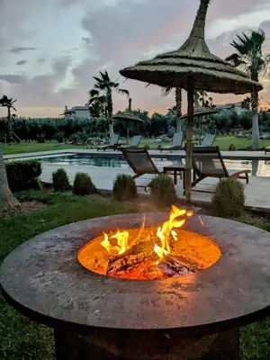 a fire pit in a yard with an umbrella at Villa Sbaa Marrakech in Marrakech