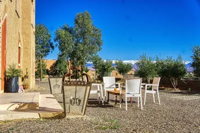 a patio with white chairs and a table and a tree at lmtounipalace in Ouarzazate
