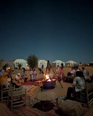a group of people sitting around a camp fire at Sahara Magic Luxury Camp & Camel trek in Merzouga