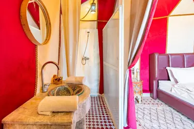 a bathroom with a sink and a mirror and a bed at Sahara Magic Luxury Camp & Camel trek in Merzouga