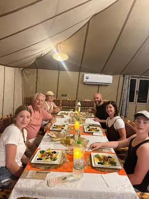 a group of people sitting around a table eating food at La Sultana Luxury Camp in Merzouga