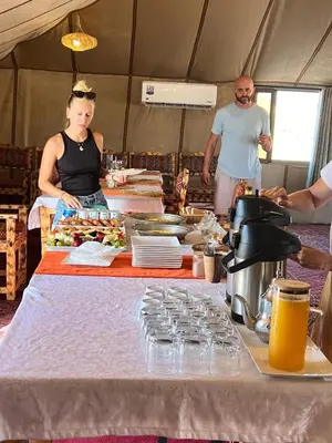 a woman standing in front of a table with food at La Sultana Luxury Camp in Merzouga