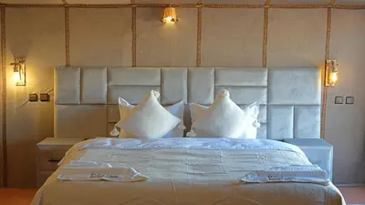 a bedroom with a large bed with white pillows at La Sultana Luxury Camp in Merzouga