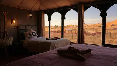 a room with two beds and a view of the desert at La Sultana Luxury Camp in Merzouga