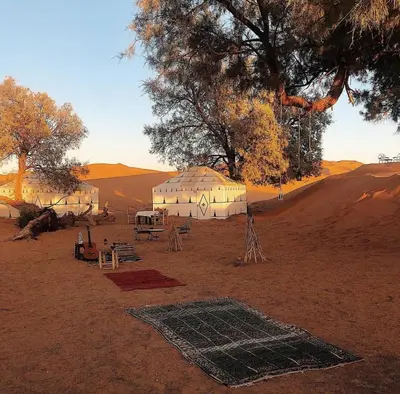 a group of tents in the middle of the desert at Merzouga Luxurious Camp in Merzouga