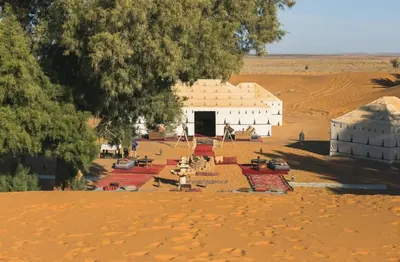 a group of buildings in the middle of a desert at Merzouga Luxurious Camp in Merzouga