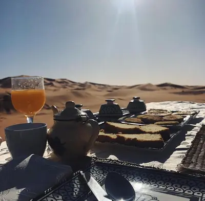 a table with food and a glass of orange juice at Merzouga Luxurious Camp in Merzouga
