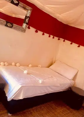 a bedroom with a white bed with a red wall at Merzouga Luxurious Camp in Merzouga