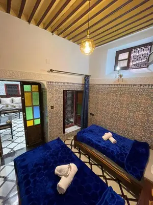 two beds in a room with blue sheets at Dar Boujloud Fez in Fès