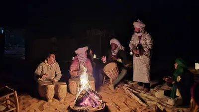 a group of people sitting around a fire at luna camp merzouga in Merzouga